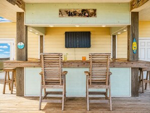 A wooden bar with two chairs and a clock on the wall. - Beachfront Home in Crystal Beach | Private Hot Tub | Double Decks | Outdoor Bar | Sleeps 16 (Crystal Beach)