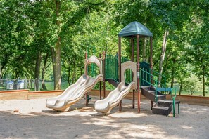 Ein Spielplatz mit zwei Rutschen, einer Kletterkonstruktion und einer kleinen Schutzhütte.