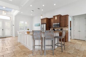 Una cocina amplia con una isla central, armarios de madera y un refrigerador de acero inoxidable.
