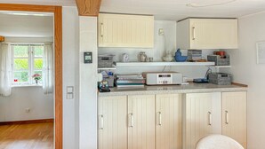 A compact kitchen with white cabinets, a countertop with various items, and a window with curtains. - Amazing home in Korsør with WiFi (Korsør)