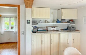 A compact kitchen with white cabinets, a countertop with various items, and a window with curtains. - Amazing home in Korsør with WiFi (Korsør)