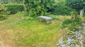 A stone bench in a garden with grass, various plants, and trees. - Amazing home in Korsør with WiFi (Korsør)