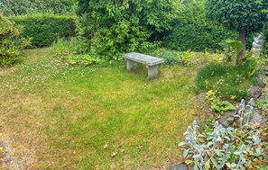 A stone bench in a garden with grass, various plants, and trees. - Amazing home in Korsør with WiFi (Korsør)
