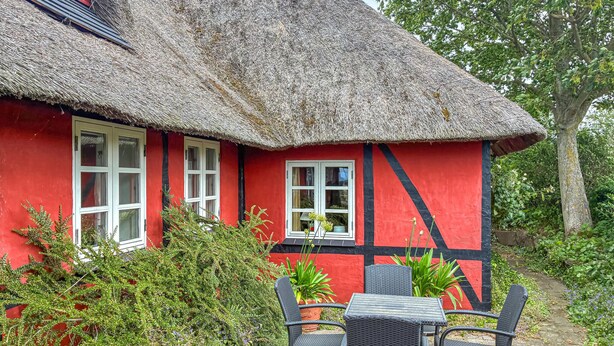A red house with a thatched roof, white windows, and a black and red striped wall. - Amazing home in Korsør with WiFi (Korsør)