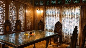 Una habitación con una mesa de vidrio, sillas de madera, techo con diseño y paneles decorativos.