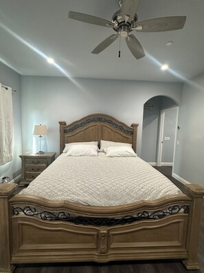 A bedroom with a wooden bed, a nightstand, a lamp, and a ceiling fan. - 3-bedroom house in superb Bonsall with cool AC and charm (Bonsall)