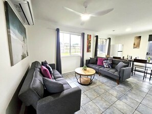 Una sala de estar con dos sofás, una mesa de centro y un ventilador de techo.