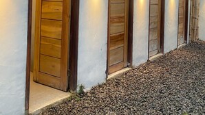 A building with multiple wooden doors and exterior lighting fixtures. - Cozzy Bantaran Riverside (pangalengan)