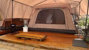 A tent with a wooden deck and seating area. - Cozzy Bantaran Riverside (pangalengan)