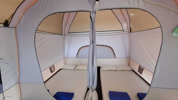 A tent with a circular entrance, two beds with blue pillows, and a central pole. - Cozzy Bantaran Riverside (pangalengan)
