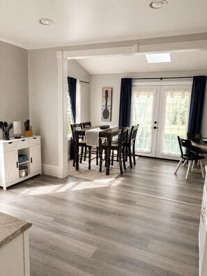 A dining area with a table and chairs, a kitchen area with cabinets, and a view through a glass door. - 3-bedroom house in lovely Painesville built in 1904! (Painesville)
