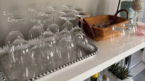 Un coin bar avec un plateau de verres à vin, un panier en bois et des bouteilles de boissons.