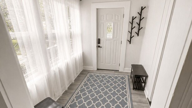 Un couloir avec un tapis à motifs, un banc, une porte et un ventilateur de plafond.