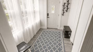 A hallway with a patterned rug, a bench, a door, and a ceiling fan.