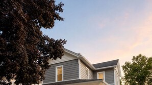Une maison à deux étages avec un porche, une allée et un jardin bien entretenu.