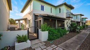 A two-story residential building with a covered patio, a gated entrance, and a landscaped garden. - Chasing Sunshine by Avantstay Shared Pool + Gazebo + Covered Patio Walk to the Beach (Port Aransas)
