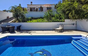 A swimming pool with steps leading into it, surrounded by outdoor furniture and a house in the background. - Cozy home in Viñuela with private swimming pool, can be inside or outside (Viñuela)