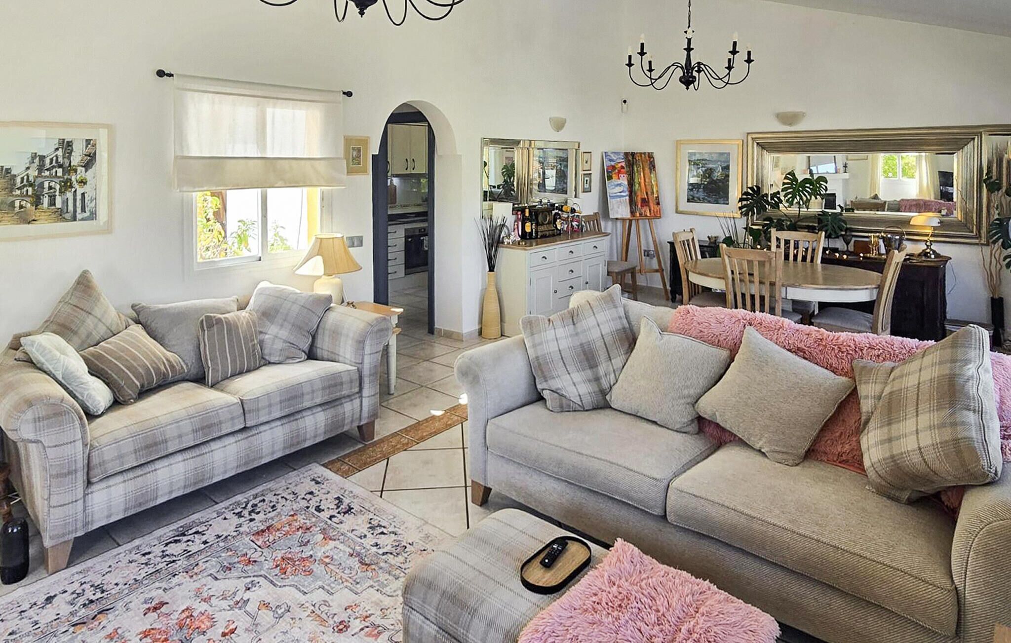 A living room with two sofas, a dining table, and a kitchen in the background.