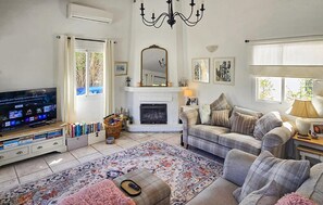 A living room with a television, fireplace, sofa, and a rug. - Cozy home in Viñuela with private swimming pool, can be inside or outside (Viñuela)