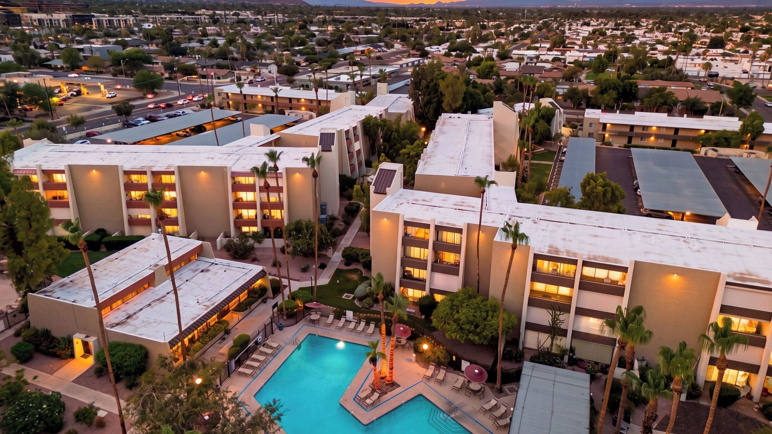 A hotel complex with multiple buildings, a swimming pool, and outdoor seating areas.