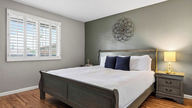 A bedroom with a bed, bedside tables, a lamp, and a window with blinds. - Camelback Cabana by Avantstay Resort Pool + Spa + Balcony Fashion Square + Echo Canyon Trail (Scottsdale)