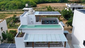 Un bâtiment moderne à deux étages, doté d’une piscine sur le toit, de panneaux solaires et offrant une vue sur le paysage environnant.