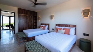 Une chambre d’hôtel avec deux lits, un ventilateur de plafond, un balcon avec des chaises et une vue sur l’extérieur.