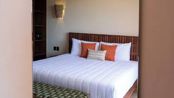 Un dormitorio con una cama grande, cabecera de madera, un banco al pie de la cama y un ventilador de techo.