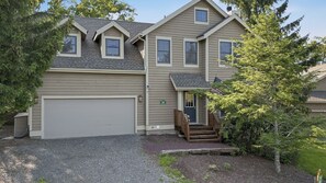Ein zweistöckiges Haus mit Garage, einer Veranda mit Treppe und einem kleinen Vorgarten.