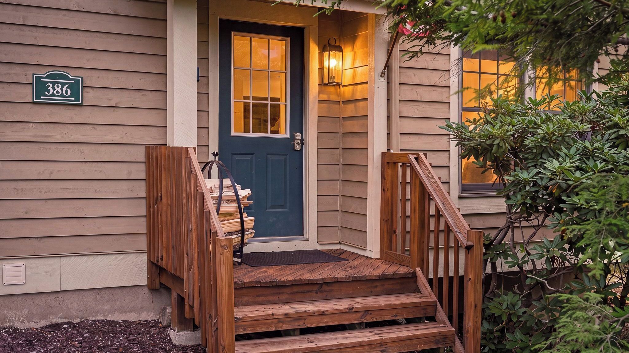 A wooden front door with a dark blue glass panel, a wooden staircase leading up to the door, and a small porch area with a wooden railing.