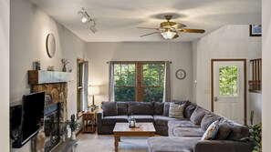 Un salon doté d’une cheminée en pierre, d’un téléviseur à écran plat, d’un canapé, d’une table basse et d’un ventilateur de plafond.