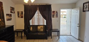 A room with a black leather sofa, a small table, a cabinet, and a door leading outside. - Delightful 3-bedroom townhome with AC in Mesa (Mesa)