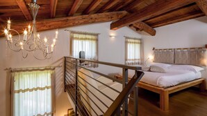 Una camera da letto con soffitto in legno, un lampadario, un letto e una scala.