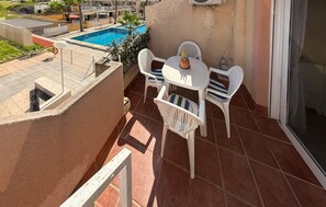 A balcony with a pool, white plastic chairs, a small table, and a potted plant. - Beautiful apartment in Guardamar del Segura with WiFi (Guardamar del Segura)