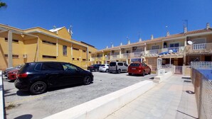 A parking lot with multiple cars and a row of residential buildings with balconies. - Beautiful apartment in Guardamar del Segura with WiFi (Guardamar del Segura)