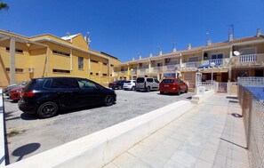 A parking lot with multiple cars and a row of residential buildings with balconies. - Beautiful apartment in Guardamar del Segura with WiFi (Guardamar del Segura)