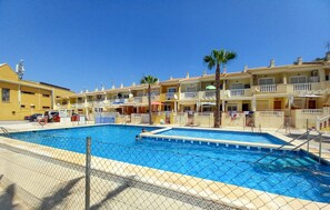 A swimming pool surrounded by a chain-link fence, with a clear blue sky above. - Beautiful apartment in Guardamar del Segura with WiFi (Guardamar del Segura)