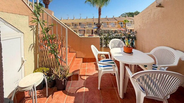 A terrace with a table and chairs, potted plants, and a view of buildings in the background. - Beautiful apartment in Guardamar del Segura with WiFi (Guardamar del Segura)