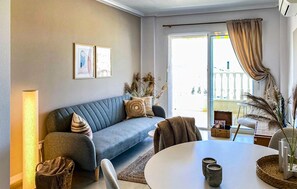 A living room with a grey sofa, a round table with candles, and a view through a glass door. - 2 bedroom awesome apartment in Rojales (Rojales)