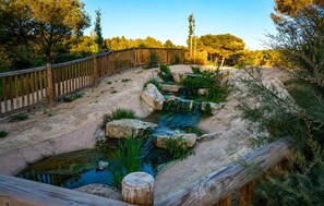 A naturalistic enclosure with a wooden fence, a small water feature, and surrounding vegetation. - 2 bedroom awesome apartment in Rojales (Rojales)
