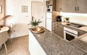A modern kitchen with granite countertops, stainless steel appliances, and a dining area with a round table and chairs. - 2 bedroom awesome apartment in Rojales (Rojales)