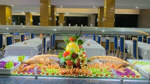 A buffet setup with seafood and vegetables, tables with blue chairs, and a modern interior with wooden accents. - Résidence Nesrine Cozy Stay in Yasmine  (Port El Kantaoui)