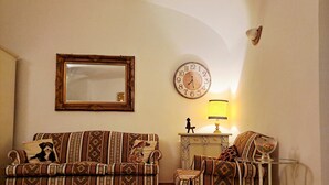 A living room with patterned sofas, a wall clock, a lamp, and a mirror. - Casa Mapi: an oasis of peace in Garbatella, just 3 metro stops from the Colosseum (Roma)