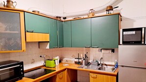 A compact kitchen with green cabinets, a microwave, a kettle, and a sink. - Casa Mapi: an oasis of peace in Garbatella, just 3 metro stops from the Colosseum (Roma)