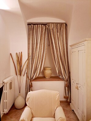 A room with a white radiator, a white chair, a white cabinet, and a window with patterned curtains. - Casa Mapi: an oasis of peace in Garbatella, just 3 metro stops from the Colosseum (Roma)
