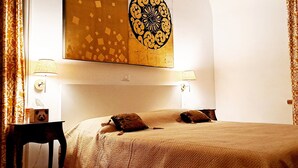 A hotel room with a large bed, two bedside lamps, a wall-mounted air conditioner, and a decorative wall piece. - Casa Mapi: an oasis of peace in Garbatella, just 3 metro stops from the Colosseum (Roma)
