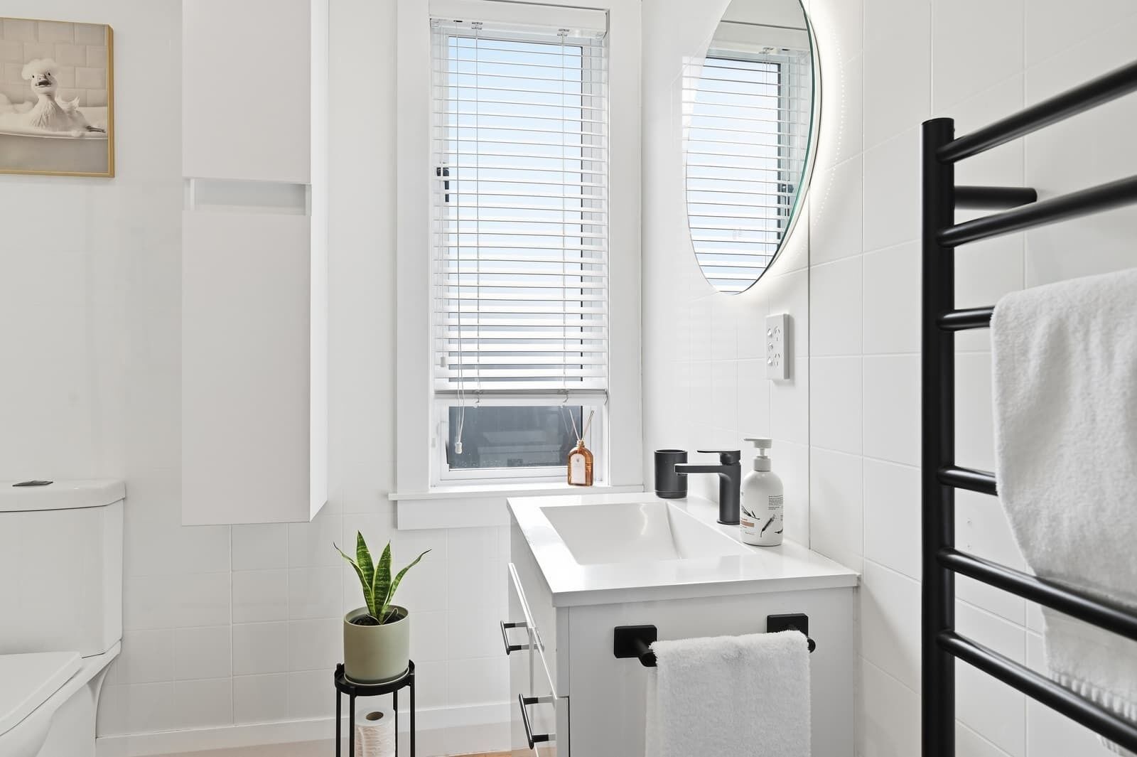 Een moderne badkamer met toilet, wastafel en handdoekrek.