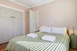 Ein Schlafzimmer mit einem Bett, zwei Nachttischen, einem Schrank und einem Kleiderschrank.