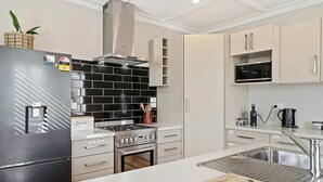A modern kitchen with a stainless steel refrigerator, a gas stove, a microwave, and a sink. - Maison Millie - Central, Pet-Friendly, Sleeps 4 (Rotorua)