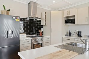 Eine moderne Küche mit einem Edelstahlkühlschrank, einem Gasherd, einer Mikrowelle und einem Spülbecken.